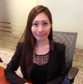 Woman smiling in an office setting, sitting at a desk.
