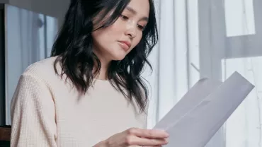 Woman reading documents by a window.