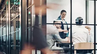 People in a glass-walled office having a meeting.
