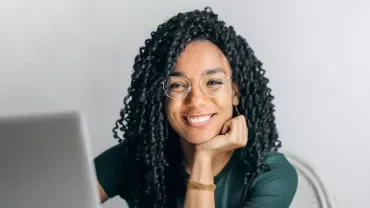 Woman with glasses smiling at a laptop
