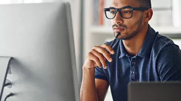 Man wearing glasses working on his computer.