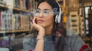 Woman listening to music with headphones in a library