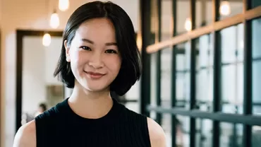 Woman smiling in a modern office hallway.