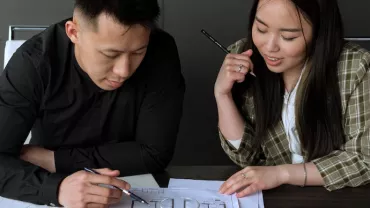 Two people discussing architectural plans at a table.