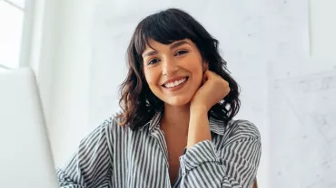 a woman smiling and sitting in front of her computer