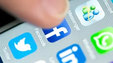 Close-up of smartphone screen showing social media app icons, including Facebook, Twitter, and WhatsApp.