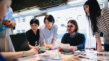 Group of professionals collaborating around a table filled with documents.