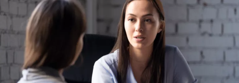 Two women engaged in a serious conversation inside an office.