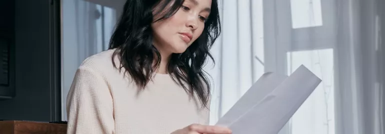 Woman reading documents by a window.