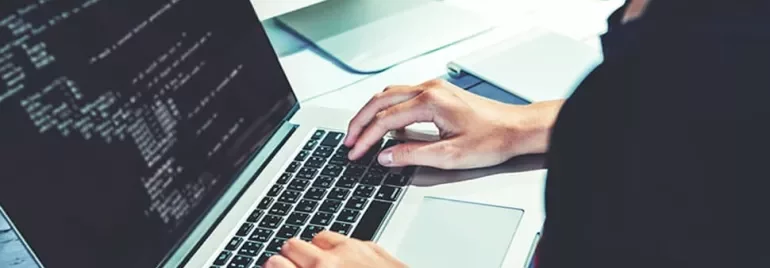 Person coding on a laptop with screen displaying lines of code.