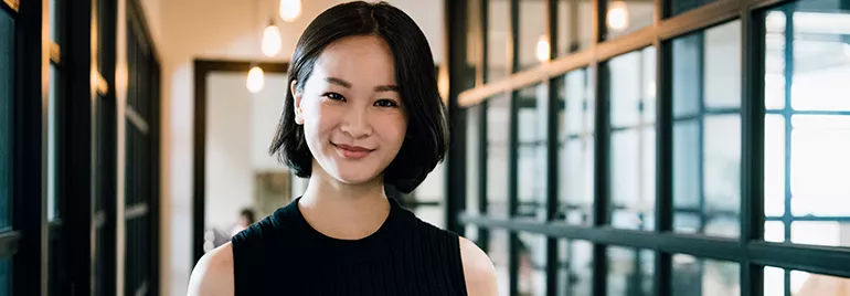 Woman smiling in a modern office hallway.