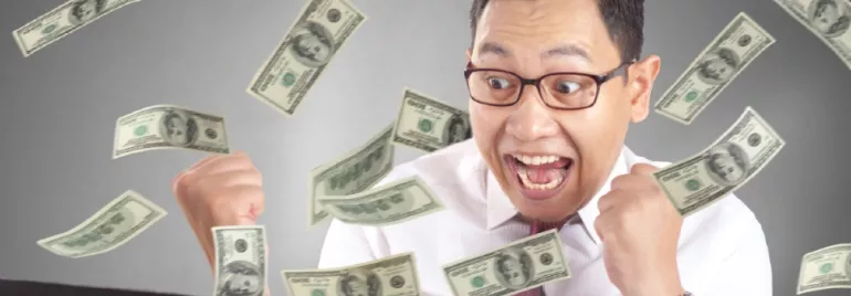 A man with an excited expression grasping dollar notes flying in the air