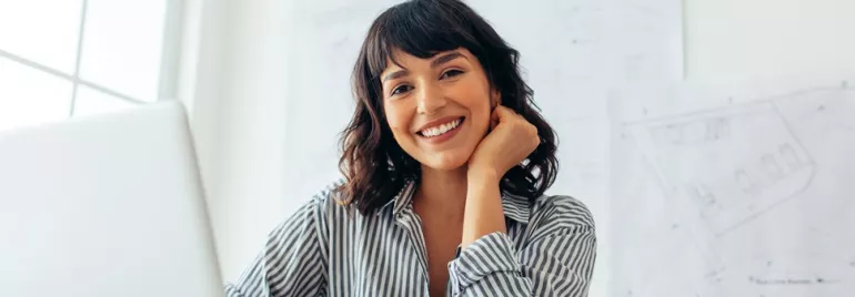 a woman smiling and sitting in front of her computer