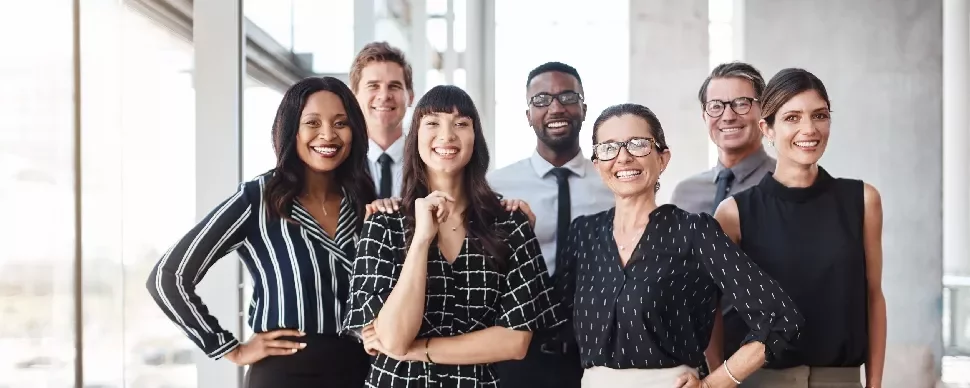 Group of diverse professionals smiling in an office setting.