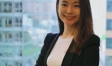 Woman smiling with arms crossed in an office building.