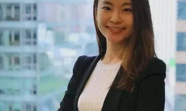 Woman smiling with arms crossed in an office building.