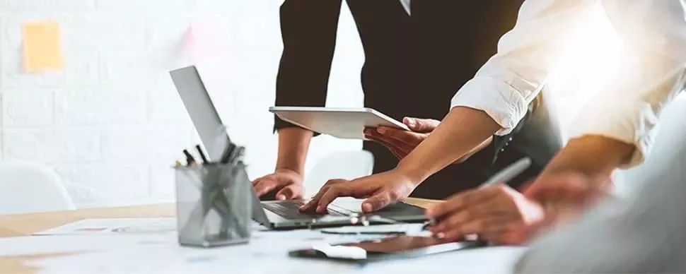 People working together at a desk with laptops and tablets.