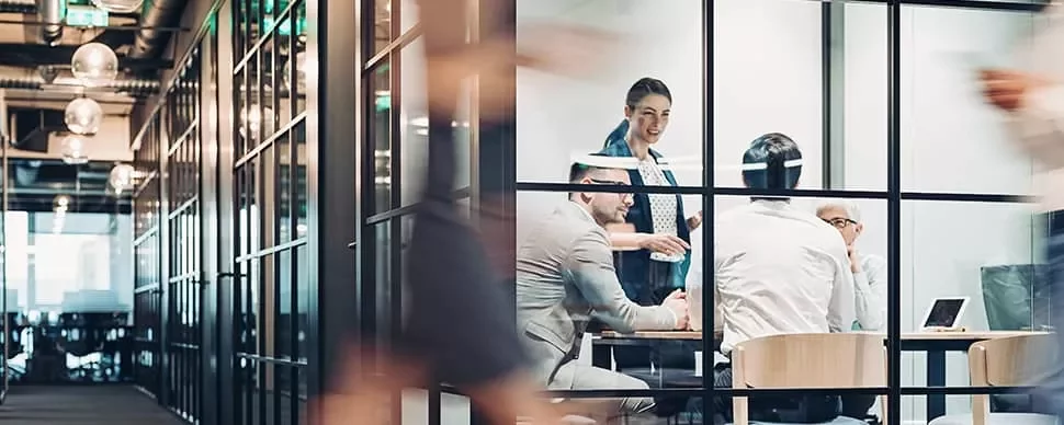 People in a glass-walled office having a meeting.