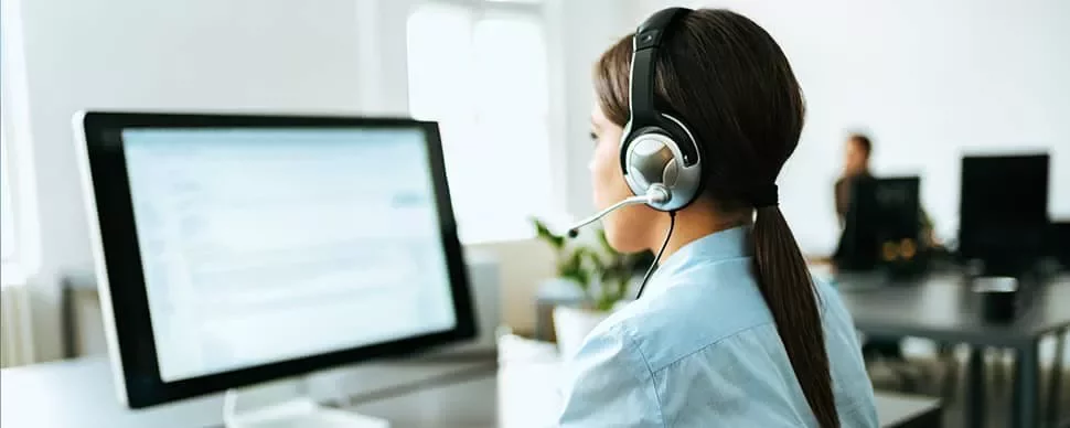 Woman with headset working at a computer in an office.