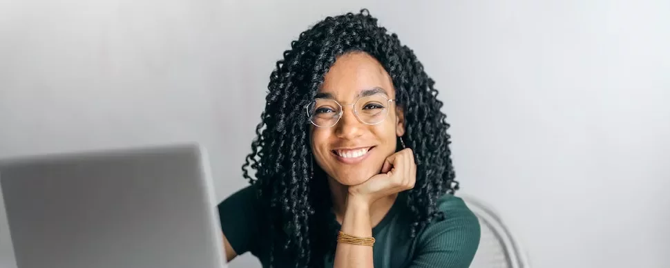 Woman with glasses smiling at a laptop