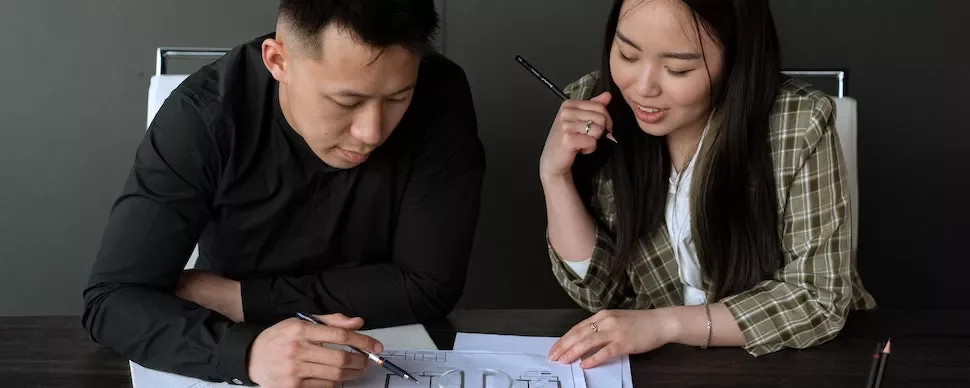 Two people discussing architectural plans at a table.