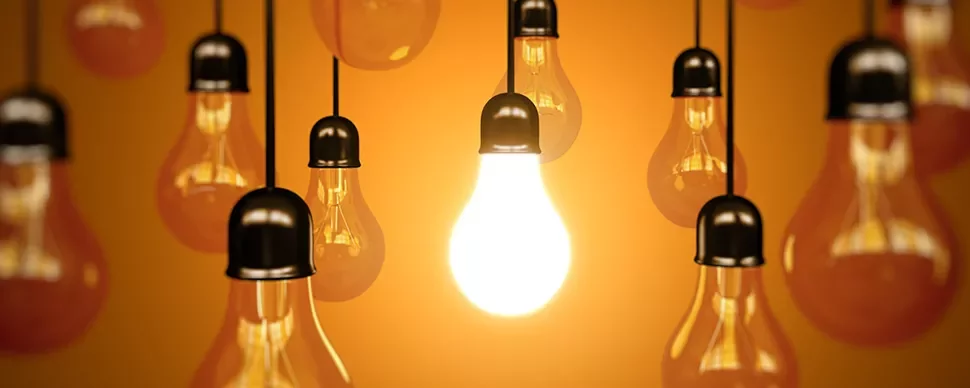 A group of hanging lightbulbs with one brightly lit.