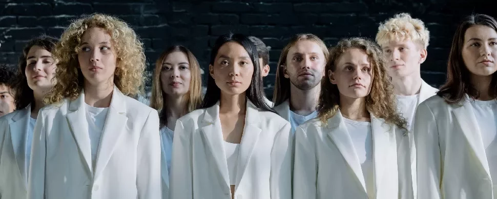 A group of people in white suits standing against a dark background.