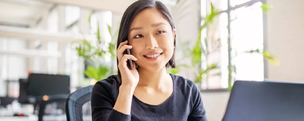 Woman smiling while on a phone call in a modern office.