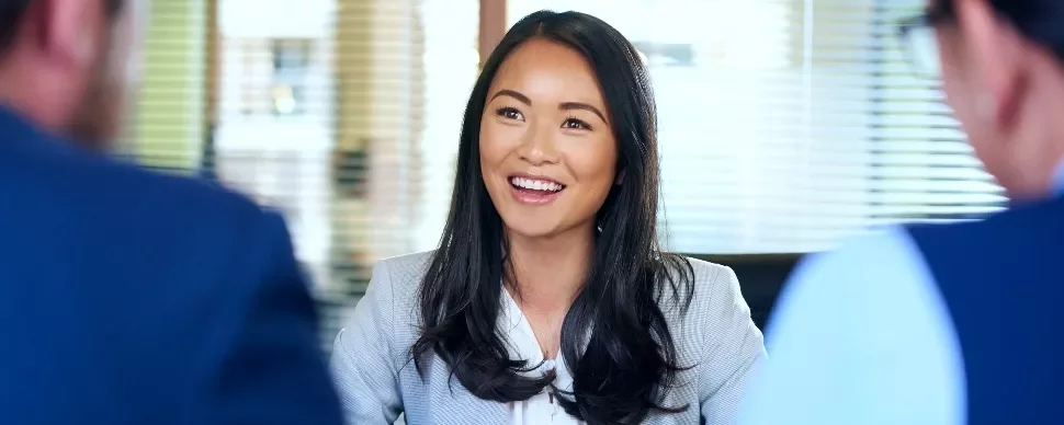 Smiling woman in an office setting, engaged in conversation.
