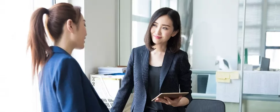 Two women in a discussion in a bright office setting.