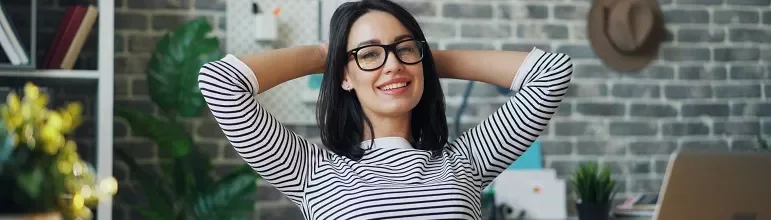 Woman in a striped shirt smiling and relaxing at her workplace.