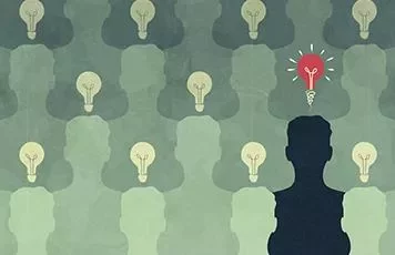 Silhouettes with light bulbs, one glowing red, symbolizing unique ideas.