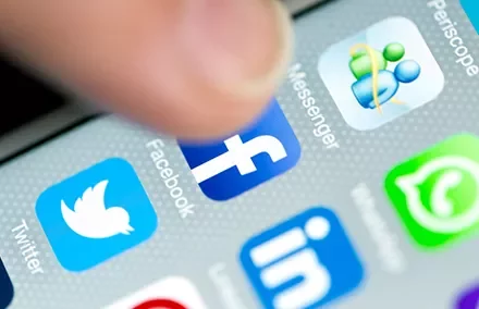 Close-up of smartphone screen showing social media app icons, including Facebook, Twitter, and WhatsApp.