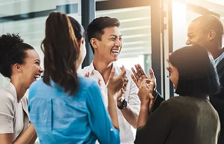 A diverse group of people laughing and clapping together.