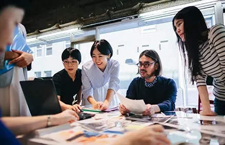 Group of professionals collaborating around a table filled with documents.