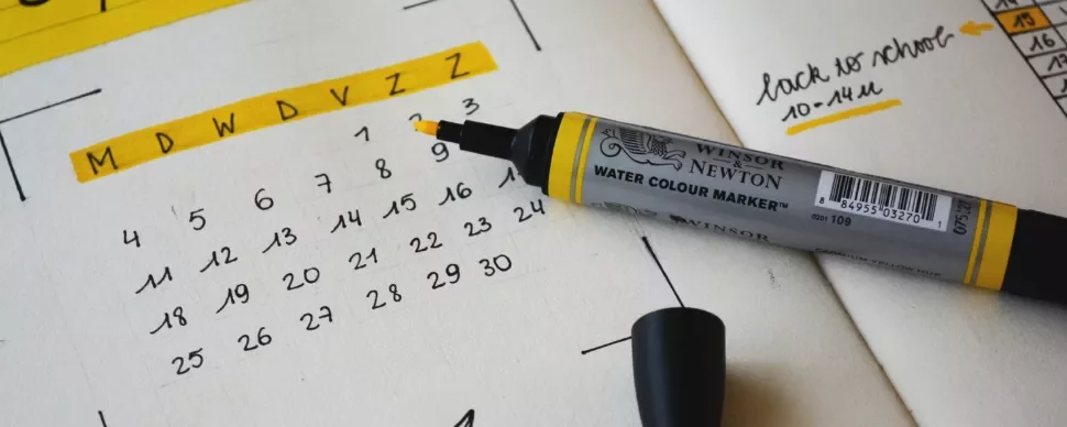 Open planner with a yellow marker on a dated calendar page.